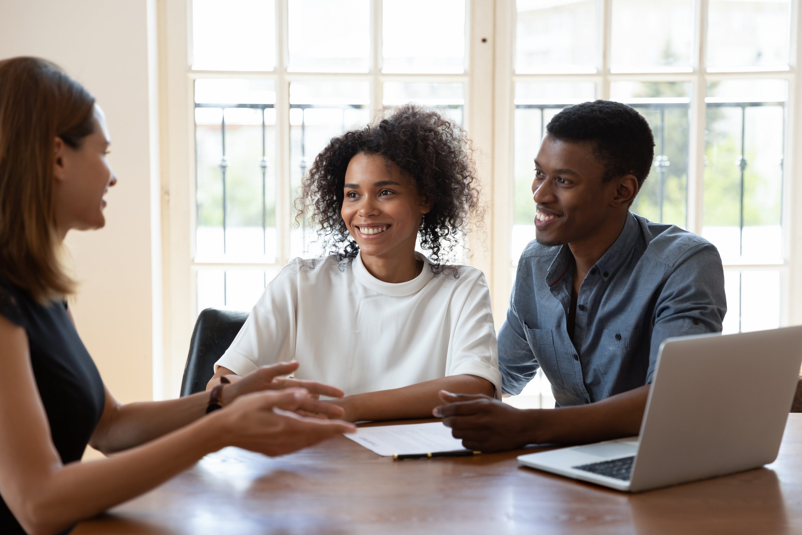 Smiling diverse clients meeting real estate agent at office.